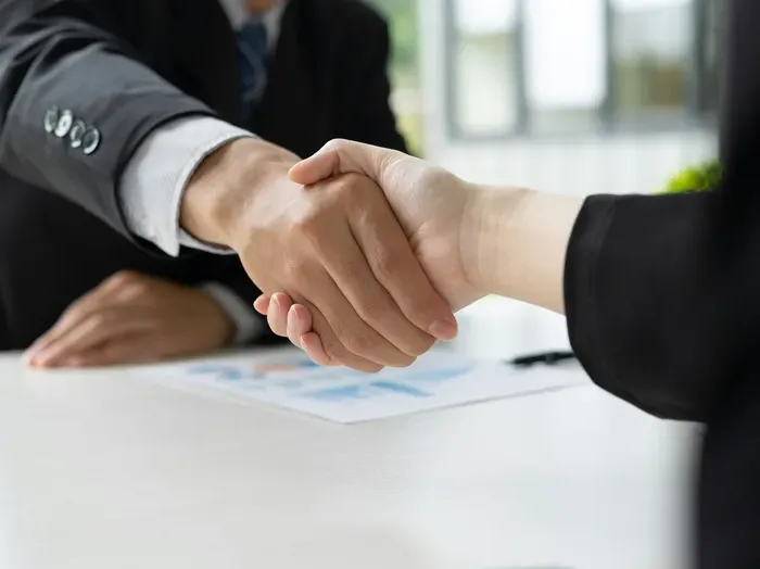 Business handshake between professionals at a meeting table, signifying trust, partnership and a successful deal